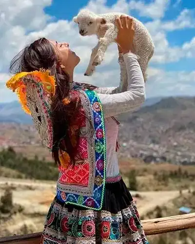 Señorita cargando una oveja con fondo del Valle Sagrado